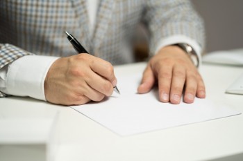 Zdjęcie ilustrujące osobę podpisującą dokument. 