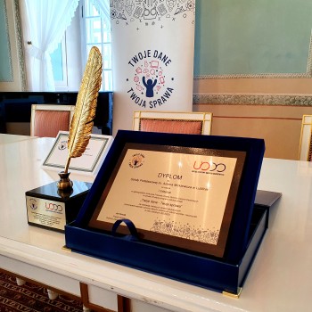 Zdjęcie prezentujące dyplom oraz statuetkę "Złotego Pióra" Prezesa UODO, które jest specjalnym wyróżnieniem w konkursie dla szkół i placówek oświatowych w konkursie edukacyjnym UODO "Twoje dane - Twoja sprawa".